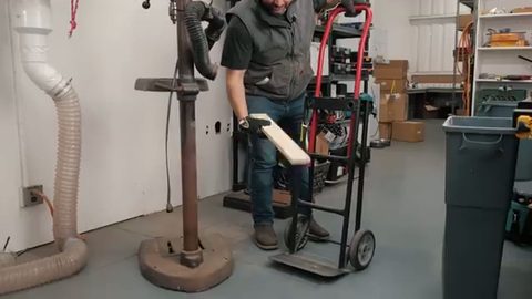 man moving a heavy shop machine on a hand-truck dolly in a garage, face visible
