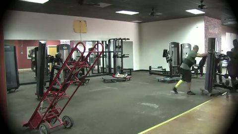 mover guiding a strength machine past a red moving hand truck