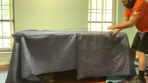 mover blanket-wrapping a large office desk